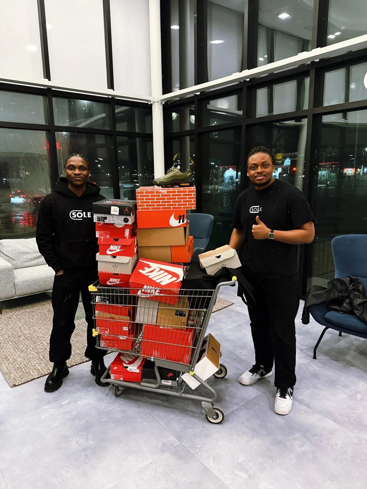 Two of the Sole Capsule founders with a cart stacked full of sneaker boxes