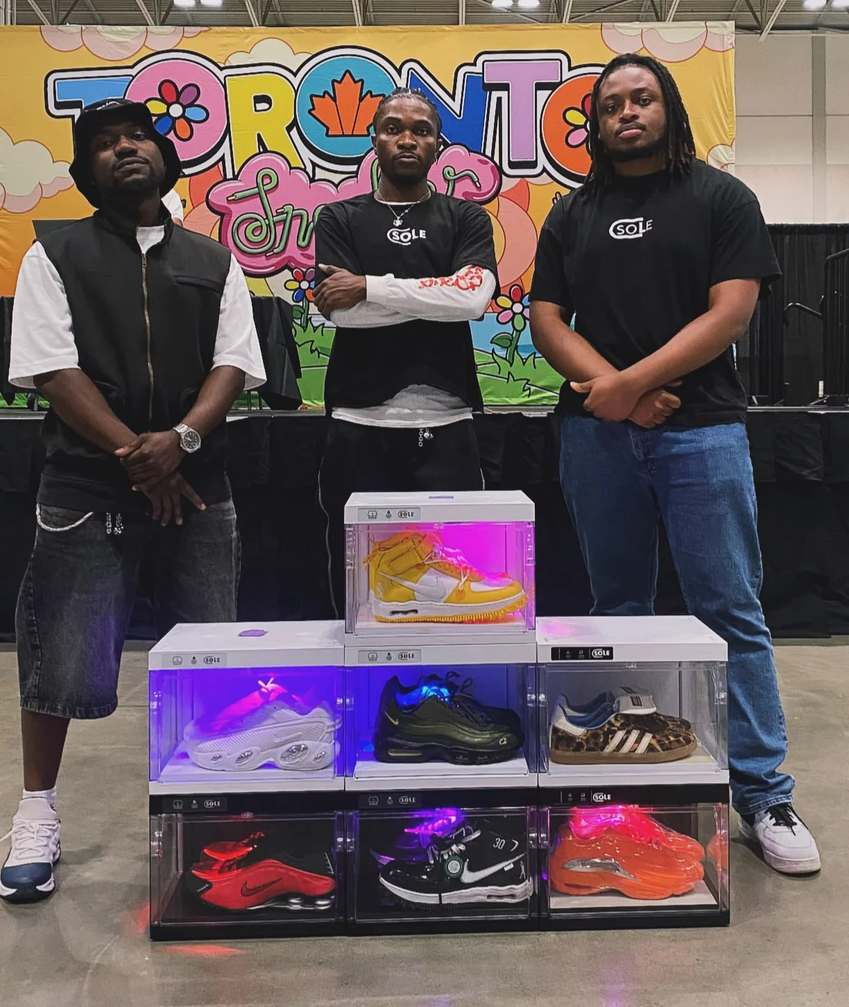 The three Sole Capsule founders at Toronto Sneaker Con behind a stack of lit Sole Pods